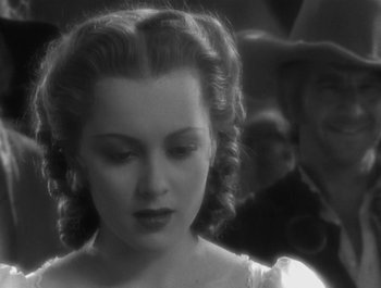 Movie still from “Captain Blood” (1935), directed by Michael Curtiz – A black and white photo of a woman in a white dress; Close Up shot, Over the shoulder angle