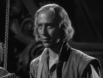Movie still from “Captain Blood” (1935), directed by Michael Curtiz – A black - and - white photo of a man with long blonde hair; Close Up shot, Over the shoulder angle