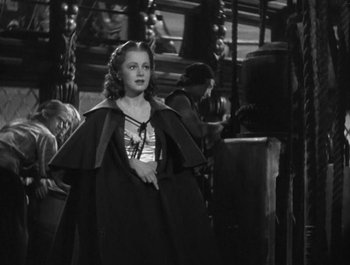 Movie still from “Captain Blood” (1935), directed by Michael Curtiz – A young woman in a long black cape; Medium shot, Over the shoulder angle