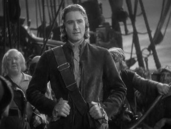 Movie still from “Captain Blood” (1935), directed by Michael Curtiz – A black and white photo of a man in a suit and tie; Medium shot, High angle