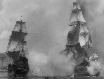 Movie still from “Captain Blood” (1935), directed by Michael Curtiz – Two ships are in the water and one ship is on fire; Extreme Wide shot, High angle