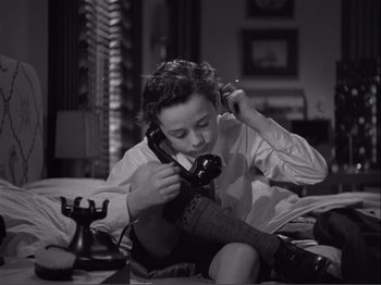 Movie still from “Captains Courageous” (1937), directed by Victor Fleming – A young girl sitting on the floor talking on a phone; Medium shot, High angle