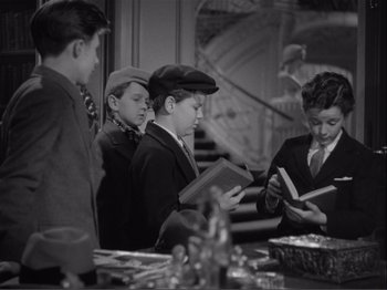 Movie still from “Captains Courageous” (1937), directed by Victor Fleming – A black and white photo of a group of young men reading books; Medium shot, High angle