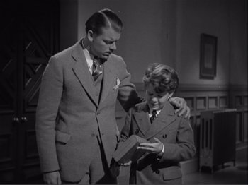 Movie still from “Captains Courageous” (1937), directed by Victor Fleming – A man and a young boy looking at something in a box; Medium shot, High angle