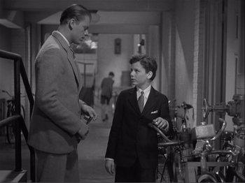 Movie still from “Captains Courageous” (1937), directed by Victor Fleming – A man and a young boy in a suit and tie talking; Medium shot, Over the shoulder angle