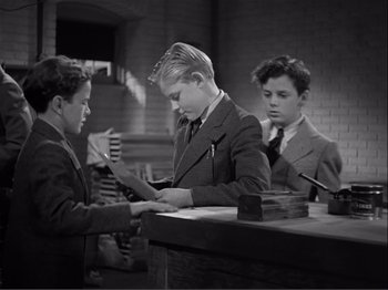 Movie still from “Captains Courageous” (1937), directed by Victor Fleming – Three young men in suits and ties looking at papers on a desk; Medium shot, High angle