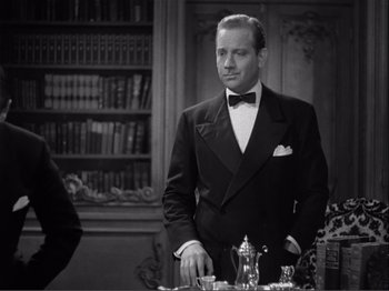 Movie still from “Captains Courageous” (1937), directed by Victor Fleming – A man in a tuxedo standing in front of a book case; Medium shot, Over the shoulder angle