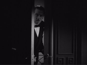 Movie still from “Captains Courageous” (1937), directed by Victor Fleming – A black and white photo of a man in a tuxedo looking through a door; Medium shot, Low angle