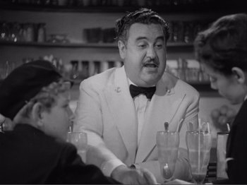 Movie still from “Captains Courageous” (1937), directed by Victor Fleming – A man sitting at a table with two other people; Medium shot, Over the shoulder angle