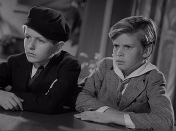 Movie still from “Captains Courageous” (1937), directed by Victor Fleming – Two young boys sitting next to each other at a table; Medium shot, High angle