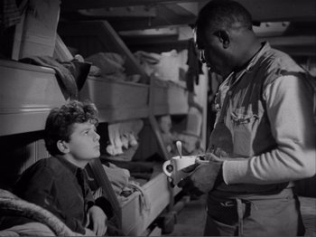 Movie still from “Captains Courageous” (1937), directed by Victor Fleming – A black and white photo of a man handing a pen to a young boy; Medium shot, High angle