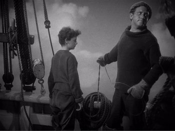 Movie still from “Captains Courageous” (1937), directed by Victor Fleming – A man and a boy standing on a boat in the water; Medium shot, High angle