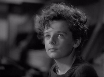 Movie still from “Captains Courageous” (1937), directed by Victor Fleming – A young man with a curly hair sitting in a room; Close Up shot, High angle