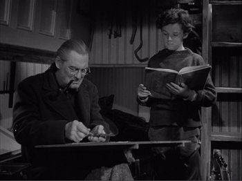 Movie still from “Captains Courageous” (1937), directed by Victor Fleming – An older man and a young woman are reading; Medium shot, Low angle