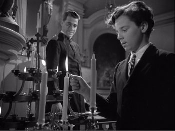 Movie still from “Captains Courageous” (1937), directed by Victor Fleming – Two young men are lighting candles in a church; Medium shot, Low angle