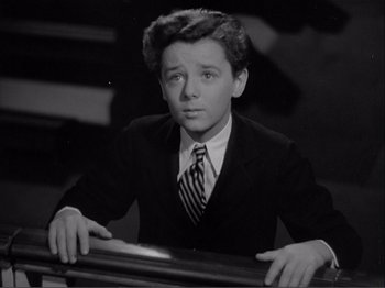 Movie still from “Captains Courageous” (1937), directed by Victor Fleming – A black and white photo of a young man in a suit and tie; Medium shot, High angle