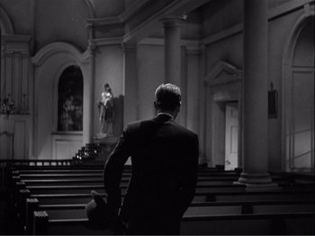 Movie still from “Captains Courageous” (1937), directed by Victor Fleming – A man in a suit standing in front of pedestals; Wide shot, Low angle
