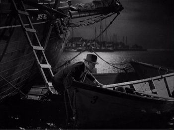 Movie still from “Captains Courageous” (1937), directed by Victor Fleming – A man in a hat is standing on a boat; Wide shot, High angle
