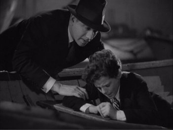 Movie still from “Captains Courageous” (1937), directed by Victor Fleming – A man in a suit and a woman in a hat are writing on a piece of paper; Medium shot, High angle