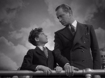 Movie still from “Captains Courageous” (1937), directed by Victor Fleming – A man and a young boy standing next to a railing; Medium shot, Low angle