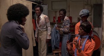 Movie still from “Car Wash” (1976), directed by Michael Schultz – A group of men standing next to each other in a room; Medium shot, Low angle