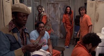 Movie still from “Car Wash” (1976), directed by Michael Schultz – A group of men in orange jumpsuits standing in a room; Medium shot, Low angle
