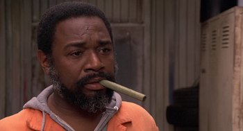 Movie still from “Car Wash” (1976), directed by Michael Schultz – A man with a beard is holding a stick in his mouth; Close Up shot, Low angle