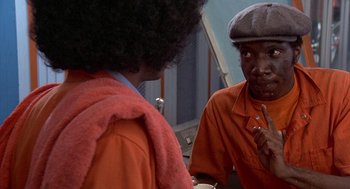 Movie still from “Car Wash” (1976), directed by Michael Schultz – A man in an orange shirt talking to another man in an orange shirt; Close Up shot, Over the shoulder angle