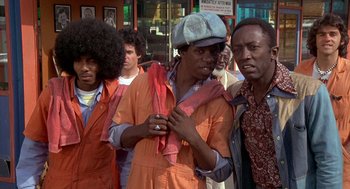 Movie still from “Car Wash” (1976), directed by Michael Schultz – A group of men standing next to each other on the street; Medium shot, Low angle