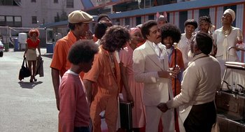 Movie still from “Car Wash” (1976), directed by Michael Schultz – A group of men standing next to each other on the street; Medium shot, Low angle