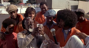 Movie still from “Car Wash” (1976), directed by Michael Schultz – A group of men standing next to each other; Medium shot, High angle