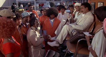 Movie still from “Car Wash” (1976), directed by Michael Schultz – A group of people standing next to each other on the street; Wide shot, Low angle