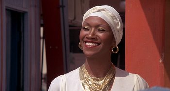 Movie still from “Car Wash” (1976), directed by Michael Schultz – A woman wearing a head scarf and a gold necklace smiles; Close Up shot, Low angle