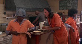 Movie still from “Car Wash” (1976), directed by Michael Schultz – Two men in orange jumpsuits preparing food in a kitchen; Medium shot, High angle