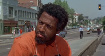 Movie still from “Car Wash” (1976), directed by Michael Schultz – A man with a beard is listening to music on the street; Close Up shot, Low angle