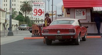 Movie still from “Car Wash” (1976), directed by Michael Schultz – A woman standing next to a parked red car; Wide shot, Low angle