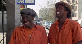 Movie still from “Car Wash” (1976), directed by Michael Schultz – A couple of men standing next to each other on a street; Medium shot, Low angle