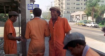 Movie still from “Car Wash” (1976), directed by Michael Schultz – A man in an overalls talking to another man in an overalls; Medium shot, Low angle