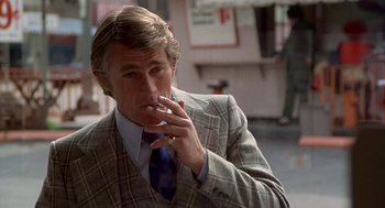 Movie still from “Car Wash” (1976), directed by Michael Schultz – A man in a suit and tie smoking a cigarette; Close Up shot, Over the shoulder angle