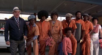 Movie still from “Car Wash” (1976), directed by Michael Schultz – A group of men in orange jumpsuits posing for a picture; Medium shot, Low angle