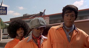 Movie still from “Car Wash” (1976), directed by Michael Schultz – A group of men standing next to each other; Medium shot, Low angle