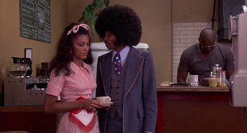 Movie still from “Car Wash” (1976), directed by Michael Schultz – A man and a woman standing next to each other; Medium shot, Over the shoulder angle