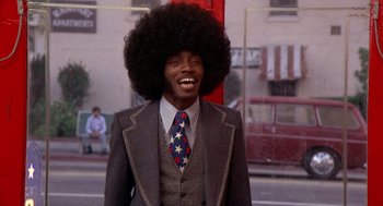 Movie still from “Car Wash” (1976), directed by Michael Schultz – A man in a suit and a tie with a large afro; Medium shot, Low angle