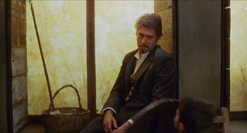 Movie still from “Caravaggio” (1986), directed by Derek Jarman – A man in a suit sitting on a bench; Medium shot, Over the shoulder angle