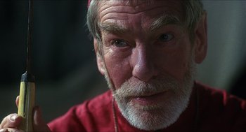 Movie still from “Caravaggio” (1986), directed by Derek Jarman – An older man with a beard and a red shirt; Close Up shot, Over the shoulder angle