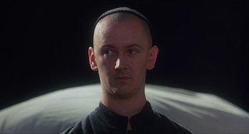 Movie still from “Caravaggio” (1986), directed by Derek Jarman – A man with a shaved head wearing a kippah; Close Up shot, Low angle