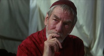 Movie still from “Caravaggio” (1986), directed by Derek Jarman – An older man wearing a red shirt and a red hat; Close Up shot, Low angle