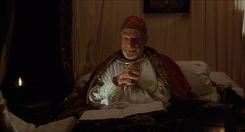 Movie still from “Caravaggio” (1986), directed by Derek Jarman – An old man sitting on a bed with a book in his hands; Medium shot, High angle
