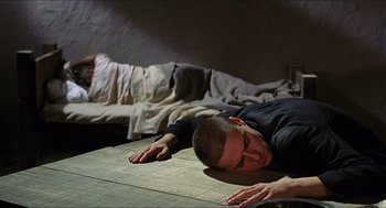 Movie still from “Caravaggio” (1986), directed by Derek Jarman – A man laying on the ground with his eyes closed; Medium shot, High angle