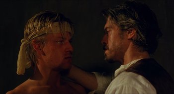 Movie still from “Caravaggio” (1986), directed by Derek Jarman – Two men are facing each other in a dark room; Close Up shot, Over the shoulder angle